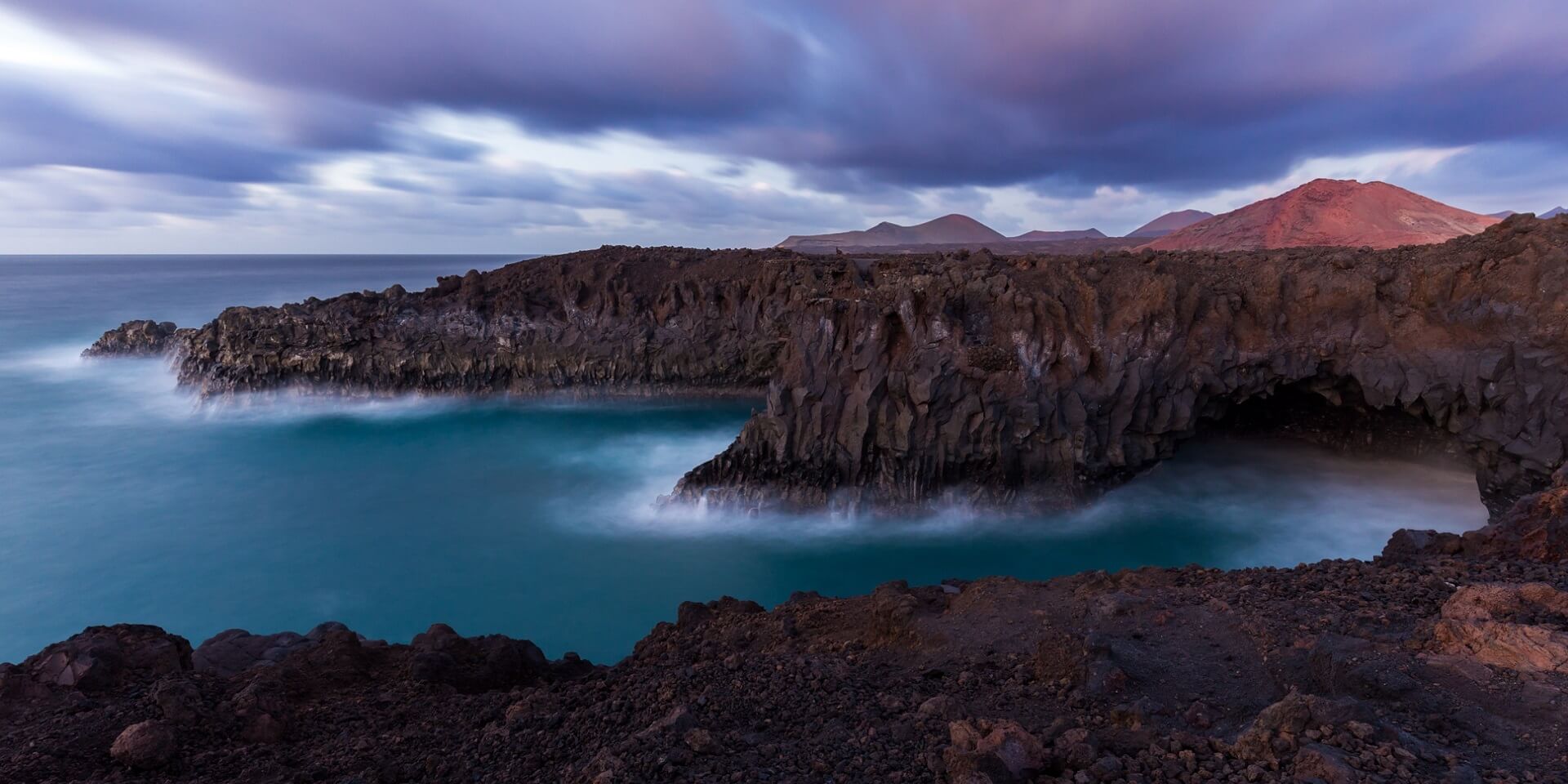 Footer A long exposure of the sea at the shore of Lanzarote after the sunset. This part of the shore is called Los Hervideros.