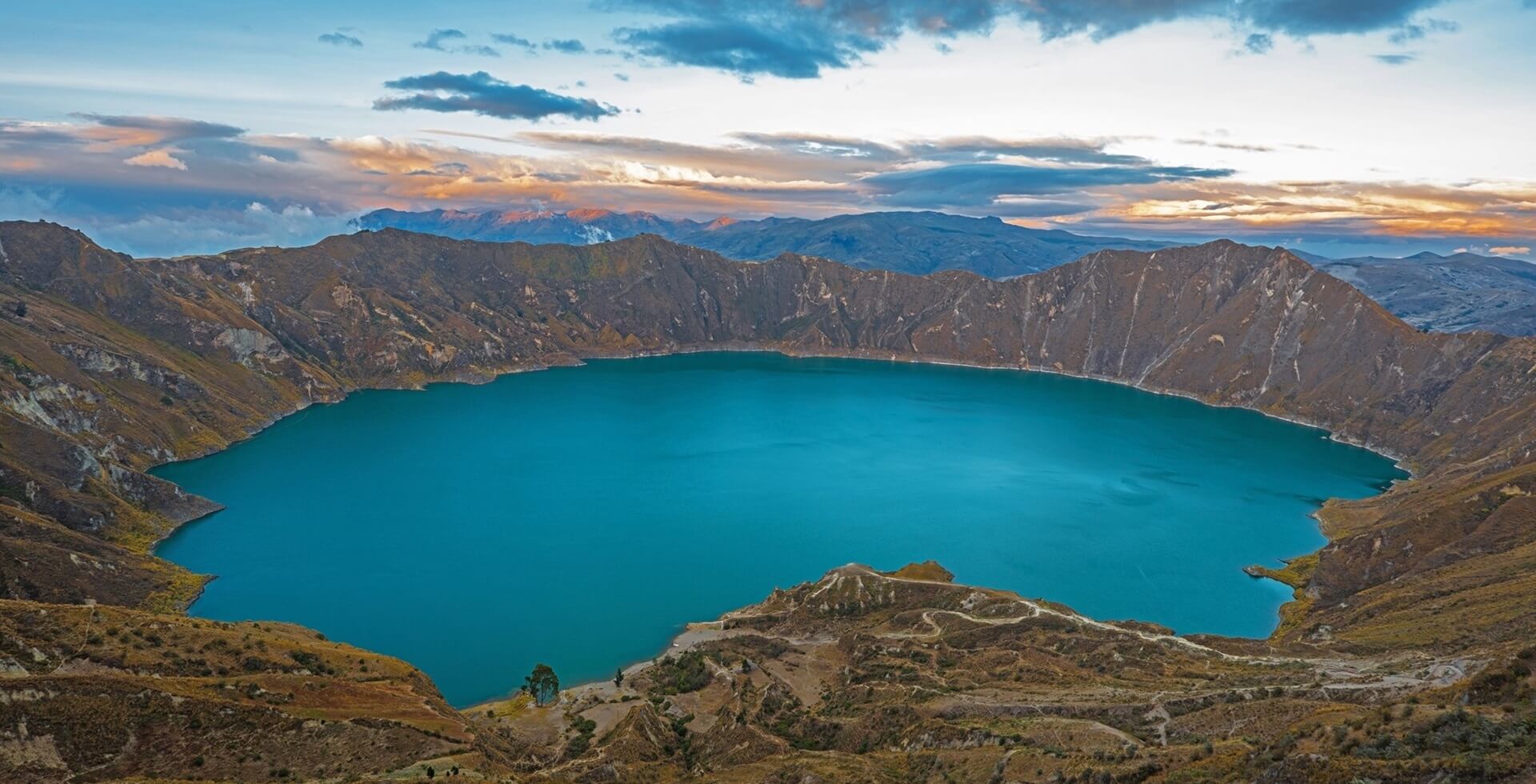 Footer active volcanic crater lake of Quilotoa at sunset located in the Andes mountain range, south of Quito, Ecuador.