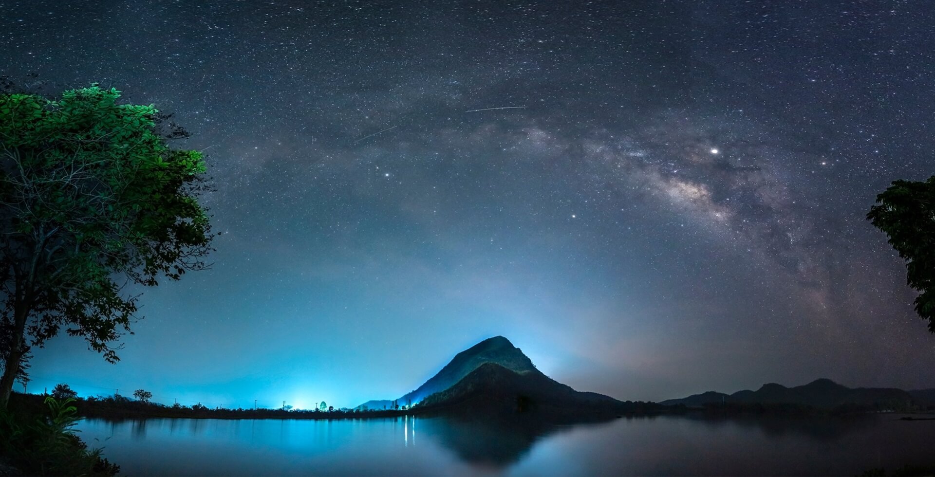Footer Night sky with stars and The Milky Way is above the mountain and reflection on the water (Lam Isu Reservoir) Kanchanaburi, Thailand